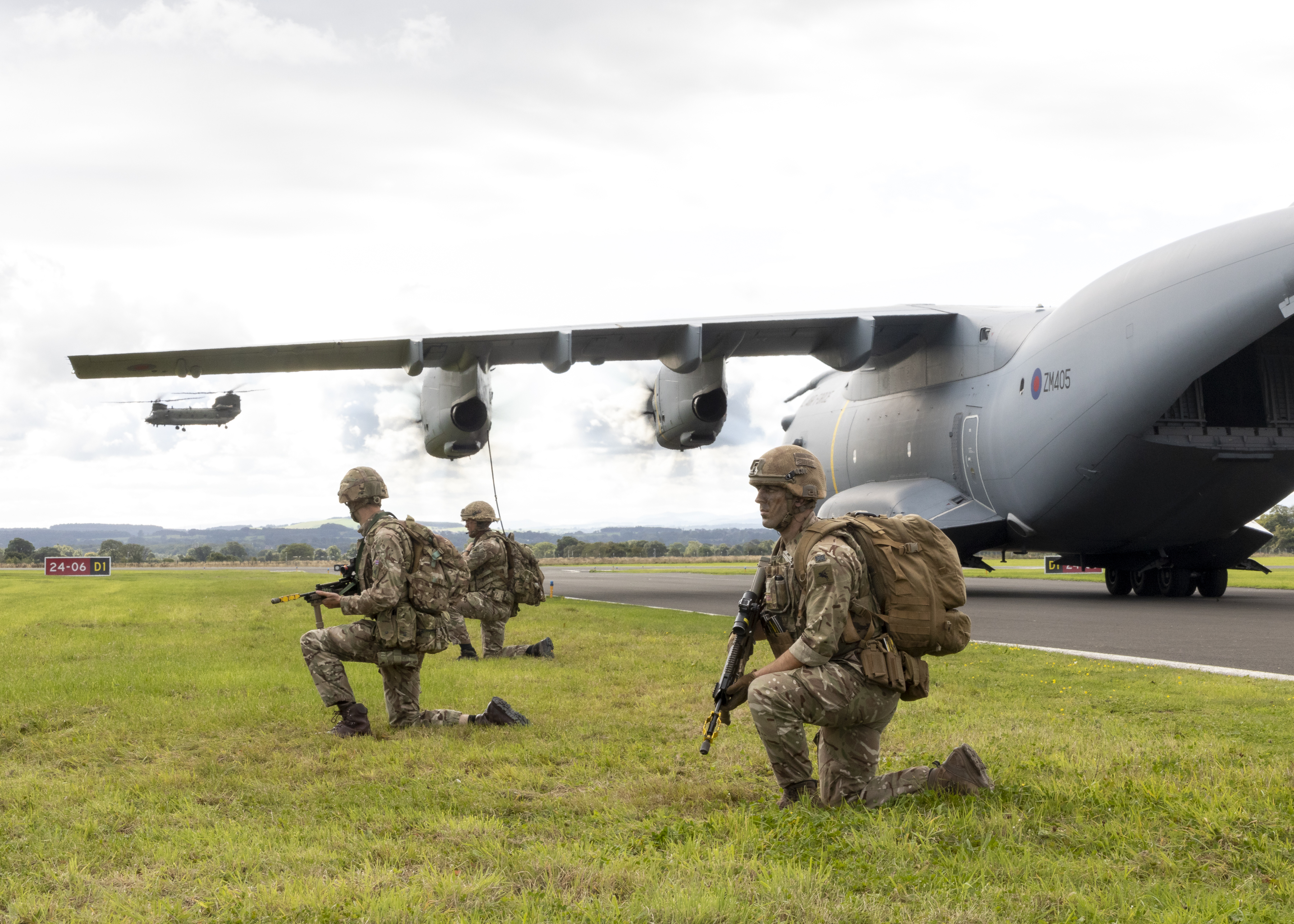 Image shows RAF Regiment with rifles kneeling by an Atlas aircraft on the airfield.